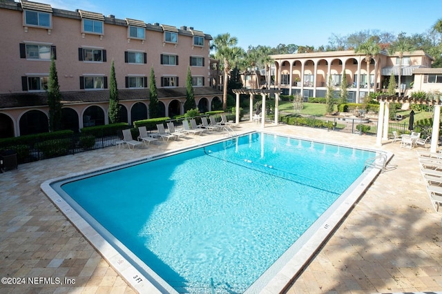 community pool featuring fence, a pergola, and a patio