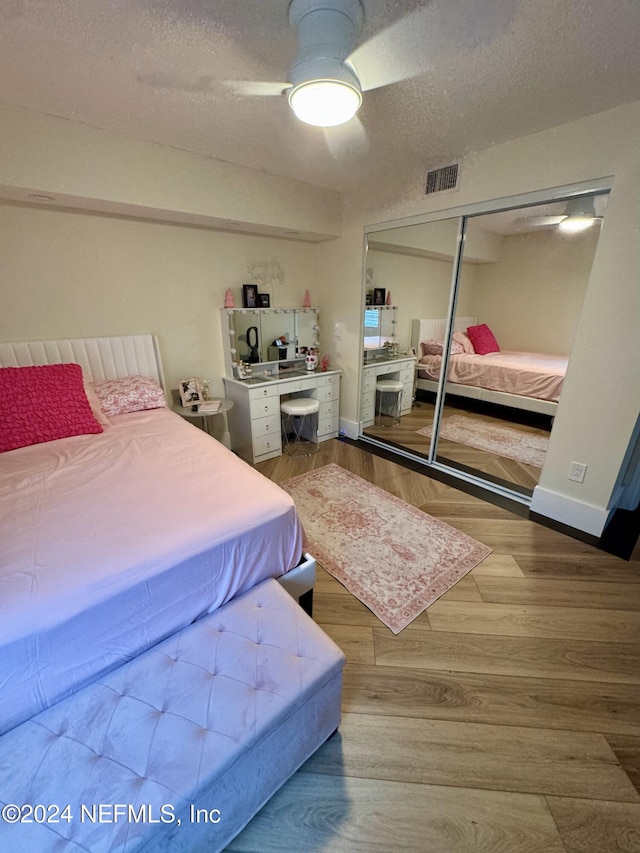 bedroom featuring hardwood / wood-style floors, a textured ceiling, a closet, and ceiling fan