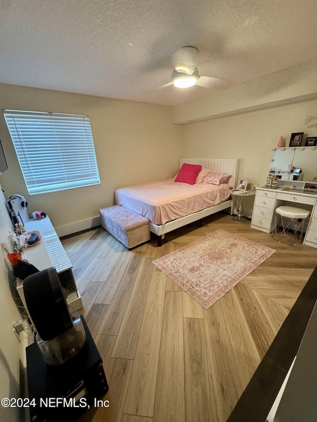 bedroom with baseboards, a textured ceiling, a ceiling fan, and wood finished floors