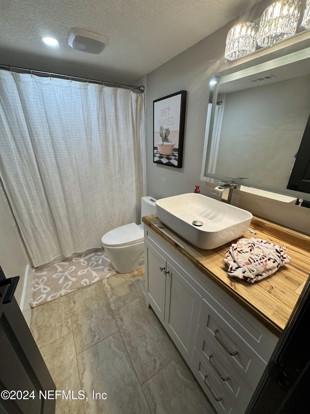 bathroom featuring vanity, a textured ceiling, and toilet