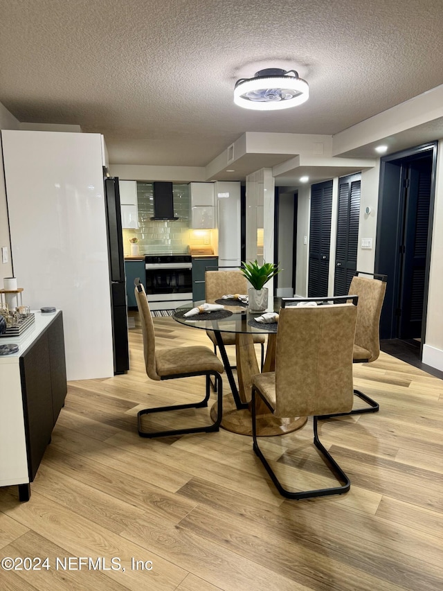 dining space with a textured ceiling and light wood-type flooring