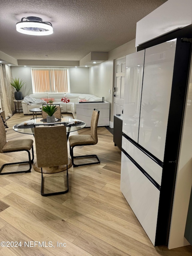 dining space featuring light hardwood / wood-style flooring and a textured ceiling