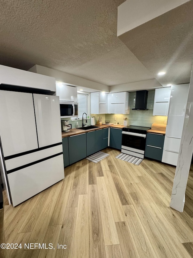 kitchen with stove, wall chimney range hood, sink, butcher block countertops, and white fridge