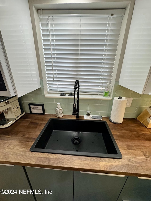 details with decorative backsplash, sink, and green cabinetry