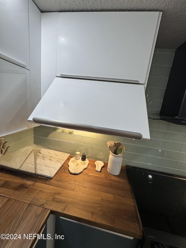 interior details featuring range, black electric cooktop, and decorative backsplash