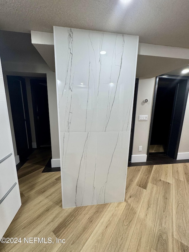 interior space with baseboards, light wood-style flooring, and a textured ceiling