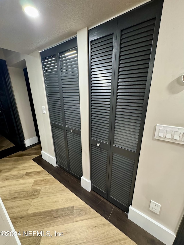 details featuring a textured ceiling, wood finished floors, and baseboards