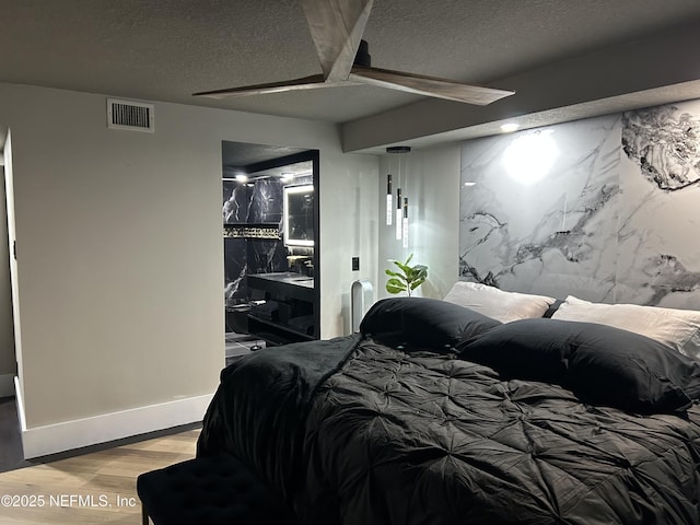 bedroom with a textured ceiling, light wood-type flooring, visible vents, and baseboards