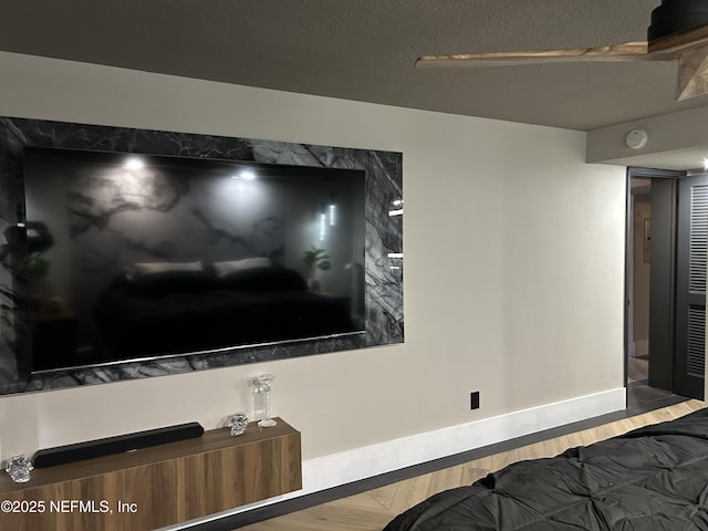 interior space with baseboards, a textured ceiling, and wood finished floors