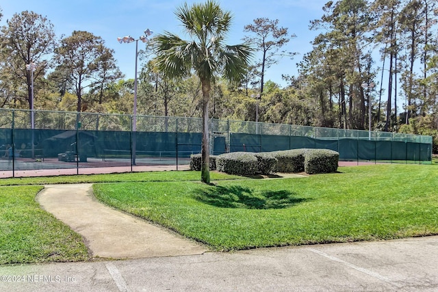 view of tennis court with a yard