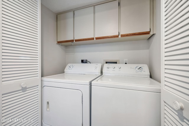 laundry area with separate washer and dryer and cabinets