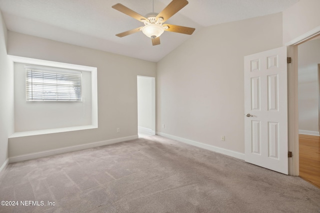 carpeted spare room featuring vaulted ceiling and ceiling fan