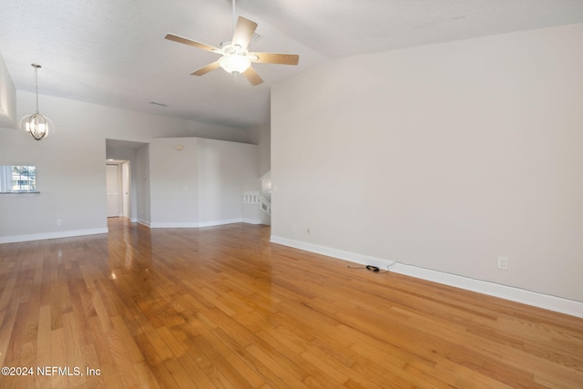 spare room with hardwood / wood-style flooring, ceiling fan with notable chandelier, a textured ceiling, and vaulted ceiling