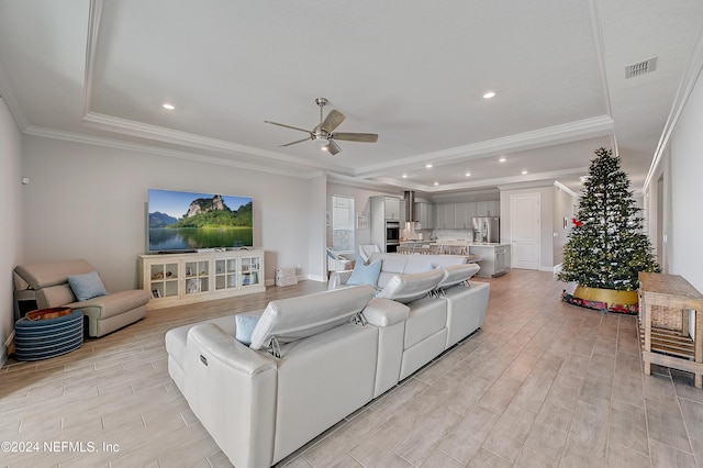 living room with ceiling fan, a raised ceiling, and crown molding