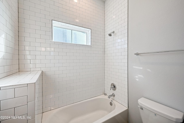 bathroom featuring tiled shower / bath combo and toilet