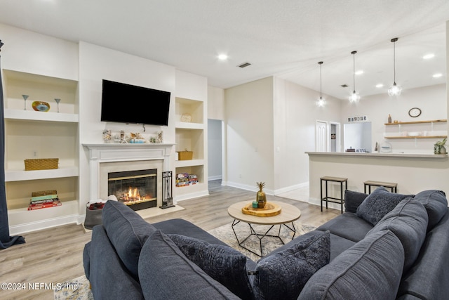 living room with built in shelves and light hardwood / wood-style flooring