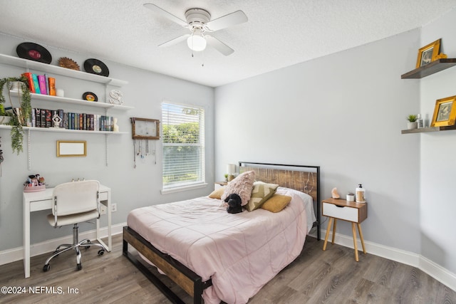 bedroom with a textured ceiling, ceiling fan, and dark wood-type flooring