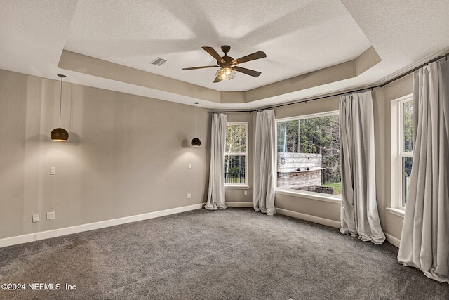 carpeted empty room featuring a textured ceiling, a tray ceiling, and ceiling fan