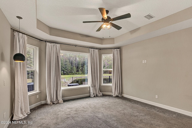 carpeted empty room featuring a tray ceiling, ceiling fan, and a textured ceiling