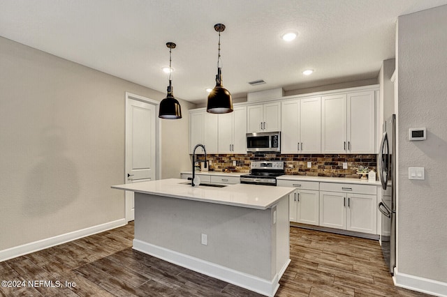 kitchen with stainless steel appliances, sink, pendant lighting, a center island with sink, and white cabinetry