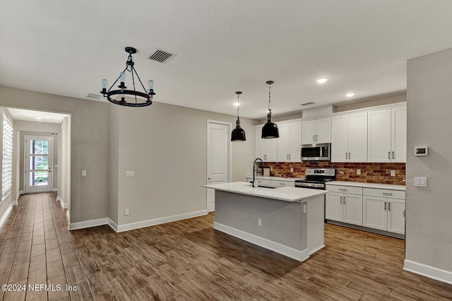 kitchen with decorative light fixtures, white cabinetry, an island with sink, and appliances with stainless steel finishes