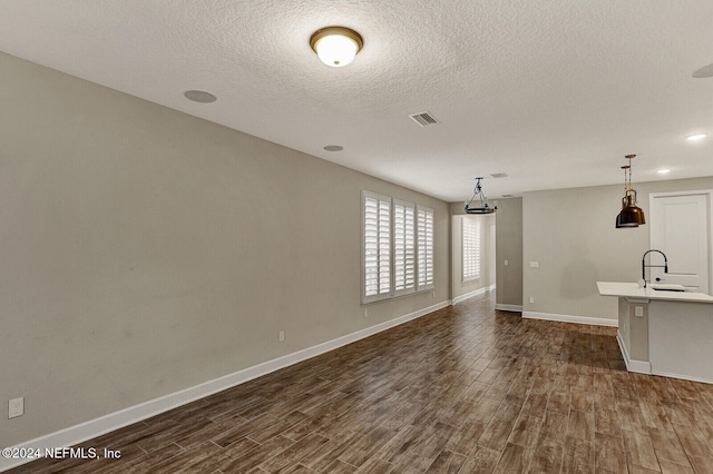 unfurnished living room with a textured ceiling and sink