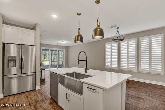 kitchen with a center island with sink, pendant lighting, white cabinetry, and appliances with stainless steel finishes