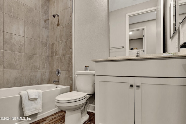 full bathroom featuring vanity, tiled shower / bath combo, hardwood / wood-style flooring, and toilet