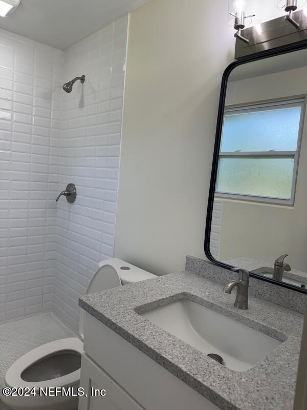 bathroom with vanity, toilet, and a tile shower