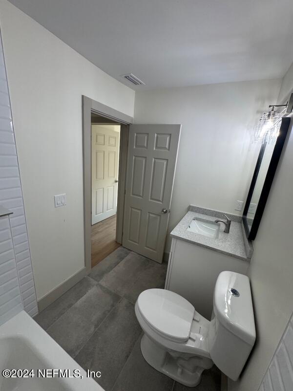 bathroom with hardwood / wood-style floors, vanity, a bathtub, and toilet