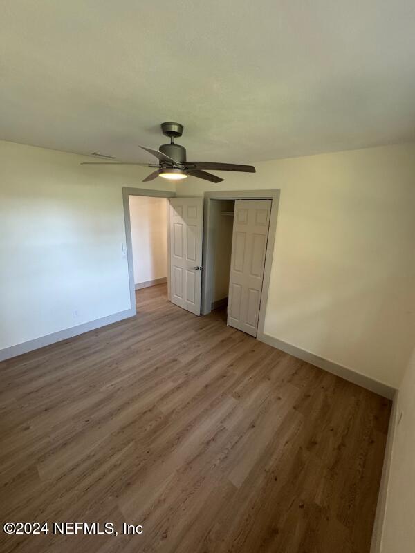 unfurnished bedroom featuring ceiling fan, a closet, and wood-type flooring