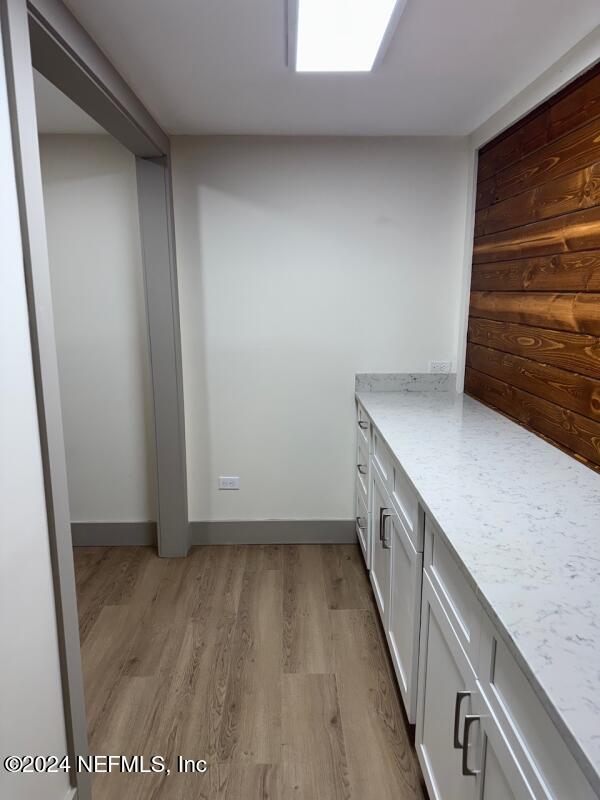 interior space with light hardwood / wood-style floors, white cabinetry, and light stone counters