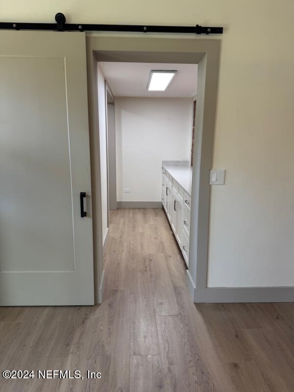 corridor with a barn door and light hardwood / wood-style floors