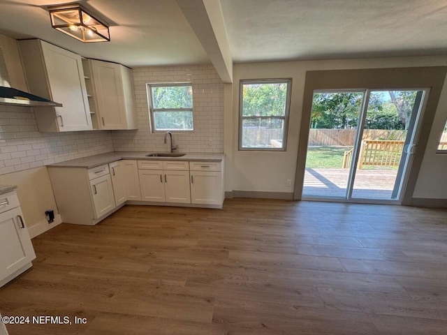 kitchen with decorative backsplash, sink, beam ceiling, white cabinets, and light hardwood / wood-style floors