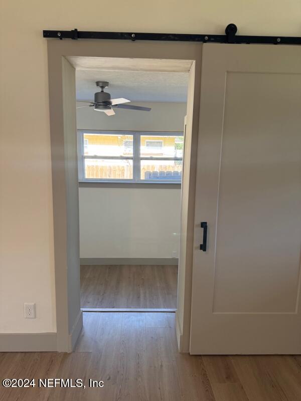 corridor featuring a barn door and light hardwood / wood-style flooring