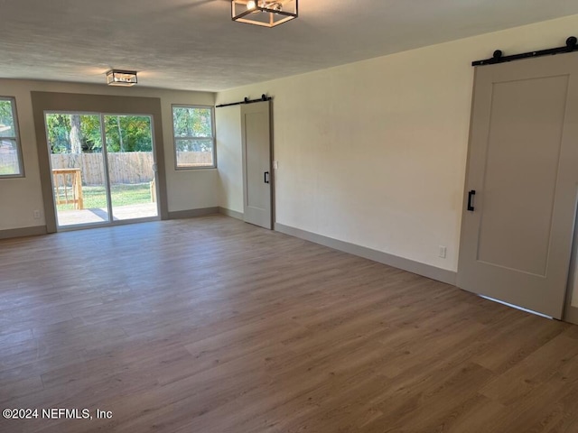 empty room featuring a barn door, light hardwood / wood-style flooring, and a textured ceiling