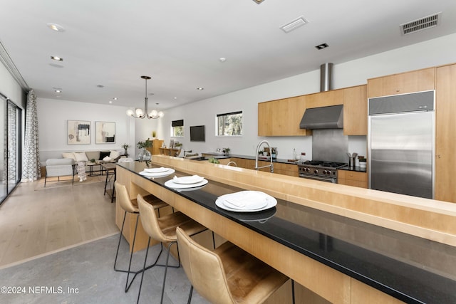 kitchen featuring a breakfast bar, extractor fan, high end appliances, decorative light fixtures, and a notable chandelier