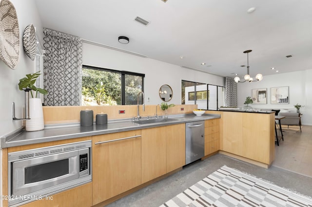 kitchen featuring sink, light brown cabinets, stainless steel appliances, an inviting chandelier, and kitchen peninsula