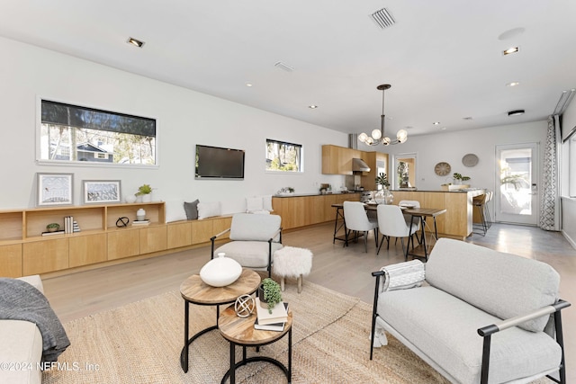 living room with plenty of natural light, light hardwood / wood-style floors, and a chandelier