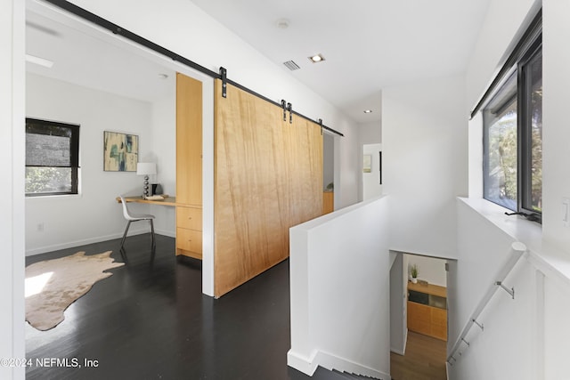 hall with a barn door, plenty of natural light, and dark wood-type flooring