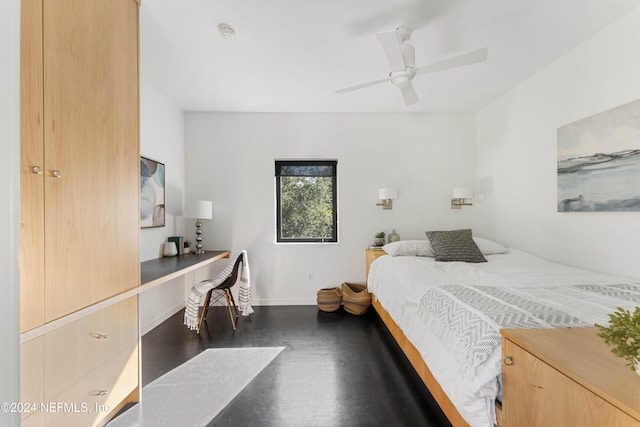 bedroom with ceiling fan, built in desk, and dark wood-type flooring