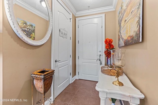 tiled entryway with a textured ceiling and ornamental molding