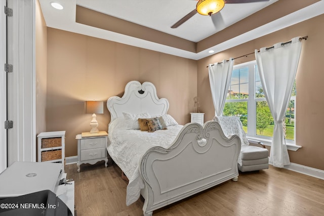 bedroom featuring a raised ceiling, ceiling fan, and hardwood / wood-style floors