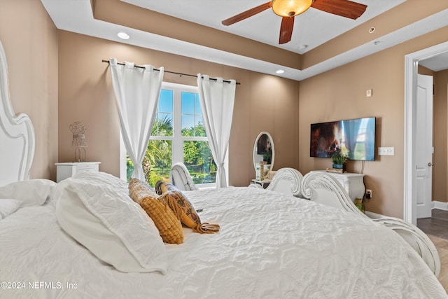 bedroom with wood-type flooring, a tray ceiling, and ceiling fan