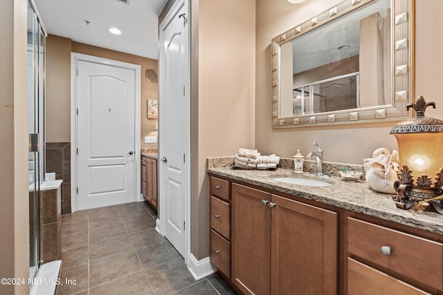 bathroom with tile patterned flooring, vanity, and walk in shower