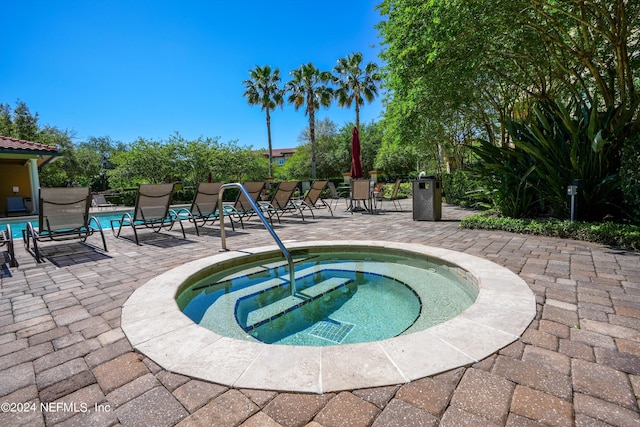 view of pool featuring a community hot tub and a patio