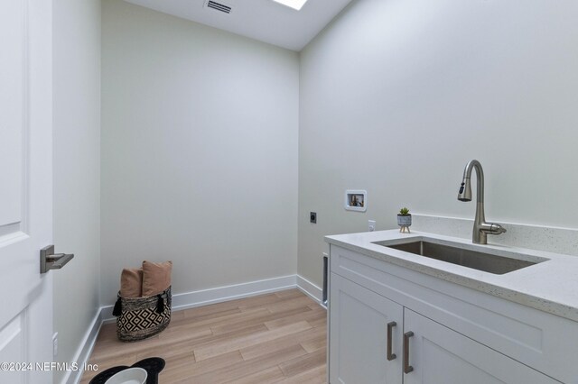 laundry room with sink, cabinets, hookup for an electric dryer, hookup for a washing machine, and light hardwood / wood-style floors