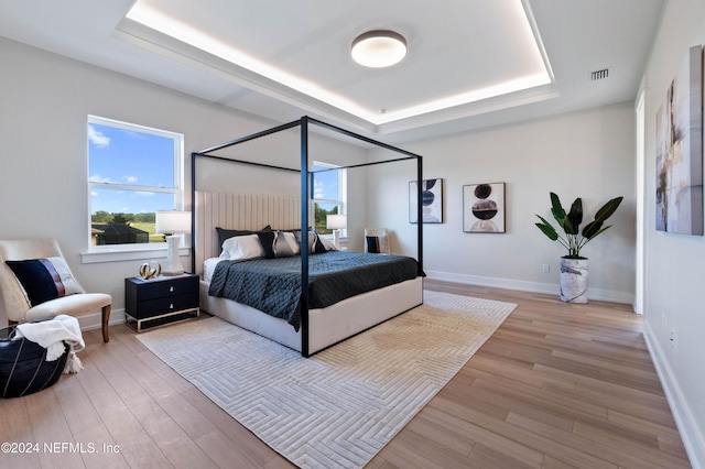 bedroom featuring a raised ceiling and light hardwood / wood-style floors