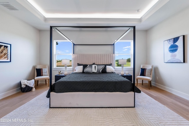 bedroom featuring light hardwood / wood-style floors and a raised ceiling