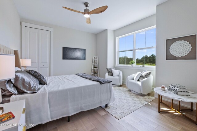 bedroom with ceiling fan, light hardwood / wood-style flooring, and a closet